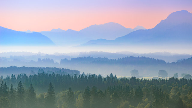 Aerial panoramic landscape of Alpine foggy foothills with morning sunrise over mountains © servickuz