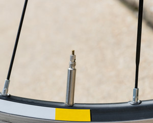 Closeup detail of bicycle tire valve stem in the "closed" position on road bike wheel.