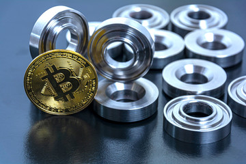 details machined on a lathe and bitcoin on a black background. The concept of real and virtual income, earnings on the Internet and in real conditions.