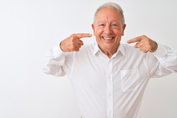 Senior grey-haired man wearing elegant shirt standing over isolated white background smiling cheerful showing and pointing with fingers teeth and mouth. Dental health concept.