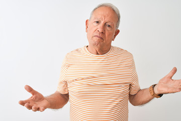 Senior grey-haired man wearing striped t-shirt standing over isolated white background clueless and...