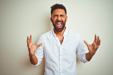 Young indian man wearing elegant shirt standing over isolated white background celebrating mad and...