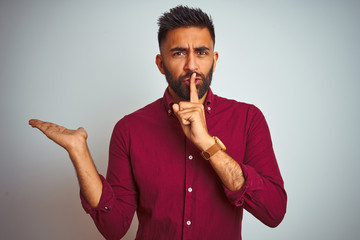 Young indian man wearing red elegant shirt standing over isolated grey background asking to be...