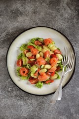 Healthy potato gnocchi salad with cherry tomatoes, cucumber, bell pepper, slightly salted salmon, olive oil and lettuce. Top view. 