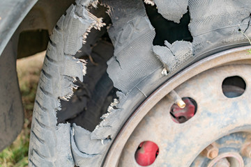 The punched and torn tire of a wheel of the car