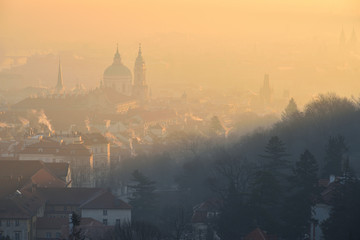 Naklejka premium Winter morning in the Mala Strana district - historical part of Prague, Czech Republic. St. Nicholas Church. Sunrise. Fog. View from the Strahov Monastery.