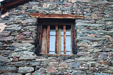 On the old window of the stone building for security, vertical wooden slats are installed