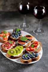 Healthy vegetarian sandwiches made from rye bread with soft cheese, organic berries and fruits - strawberries, blueberries, kiwi, figs, pomegranate seeds and mint.
