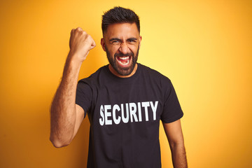 Arab indian hispanic safeguard man wearing security uniform over isolated yellow background angry...