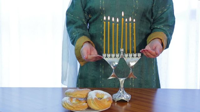 Jewish woman lights candles on Hanukkah in a beautiful candlestick.