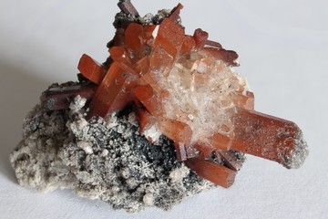 Rock matrix with small crystals and orange and clear topaz with white background