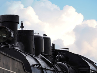 Part of an old black steam locomotive against the sky