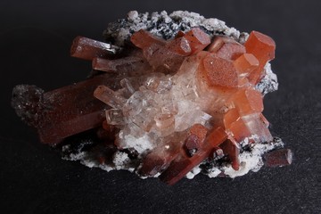 Rock matrix with small crystals and orange and clear topaz with white background