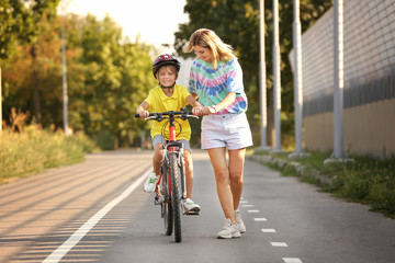 Mother teaching her son to ride bicycle outdoors