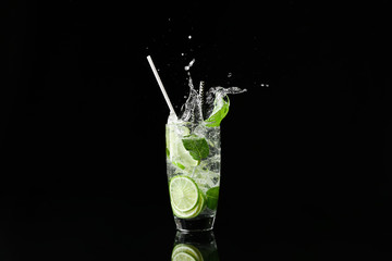 Fototapeta na wymiar Glass of fresh mojito with splashes on dark background