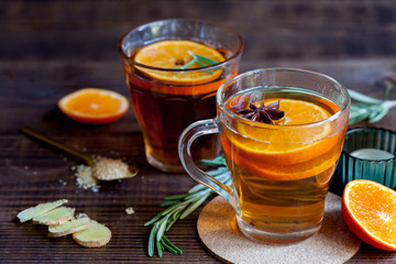 Two glasses with hot citrus tea on dark wood table, close-up