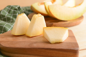 Board with slices of ripe melon on table