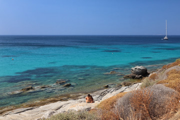 Two young girls in swimwear looking out to turquoise Aegean Sea, Agios Prokopios, Naxos, Greek Islands