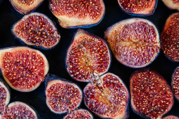 Halved ripe figs on a black background. Fall food. Tasty and healthy fig berry.
