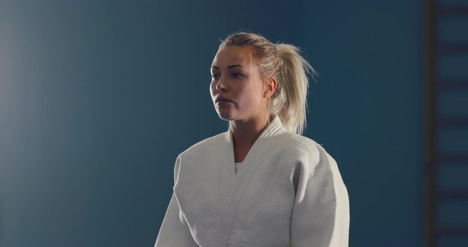 Young girl in a white kimono tunes in for a fight. Serious look of a fighter. Portrait view.