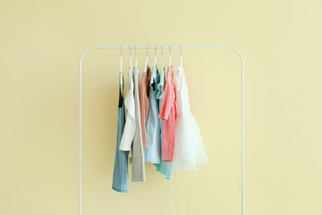 Rack with hanging clothes on color background