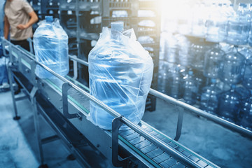 Conveyor line or belt with clean pure drinking water in plastic bottles packed in cellophane,...