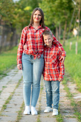 Beautiful mother and son are standing and hugging on a track in a park.