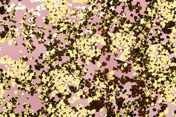 Golden confetti glitter on pink background. Festive holiday pastel backdrop. Greeteng cards template.