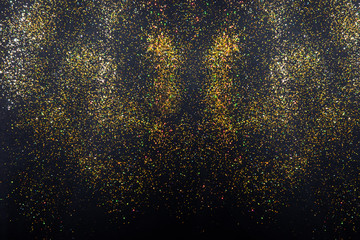 Gold glitter holiday texture on a black background. Golden explosion of confetti. Golden grainy abstract texture on a black background. Night sky style background.