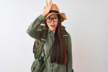 Chinese hiker woman wearing canteen hat glasses backpack over isolated white background surprised with hand on head for mistake, remember error. Forgot, bad memory concept.