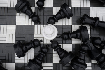 Obraz premium Large white and black chess pieces in the Park. The white pawn stands in the middle of the defeated black chess pieces