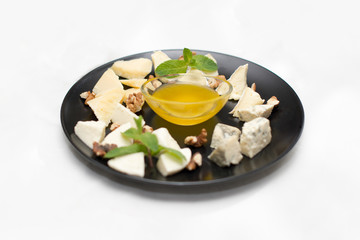 cheese platter with honey and nuts on white restaurant plate isolated on white background.
