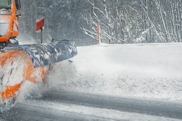Snowplow truck removing dirty snow from city street or highway after heavy snowfalls. Traffic road...
