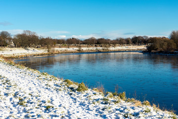 River Dee shores with green grass covered by snow during winter, Aberdeen, Scotland