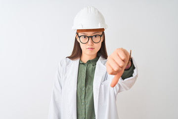 Young chinese engineer woman wearing coat helmet glasses over isolated white background looking unhappy and angry showing rejection and negative with thumbs down gesture. Bad expression.