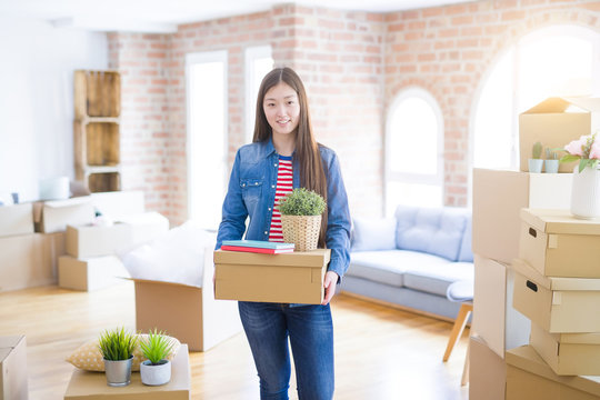 Beautiful asian young woman holding boxes, smiling happy moving to a new home