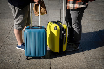 Unrecognizable two young men, travelers standing near a suitcases, summer sunny day, travel and tourism concept