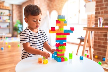 Beautiful toddler boy playing with construction blocks at kindergarten - Powered by Adobe