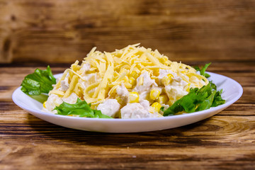 Festive salad with chicken breast, canned pineapple, cheese, sweet corn and mayonnaise on wooden table