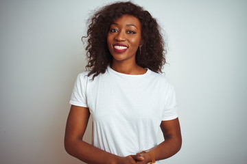 Young african american woman wearing t-shirt standing over isolated white background with hands together and crossed fingers smiling relaxed and cheerful. Success and optimistic