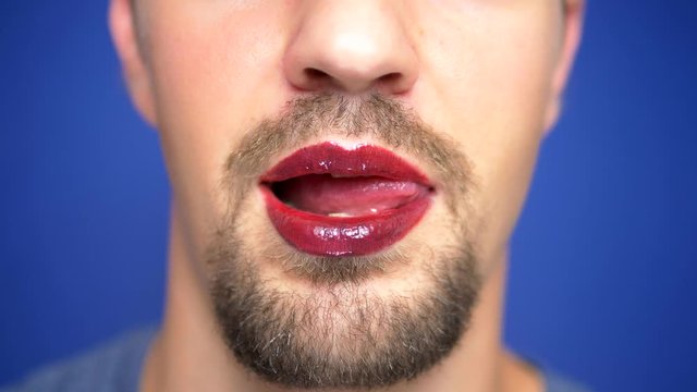 close-up. A bearded man with painted lips licks them sexually.
