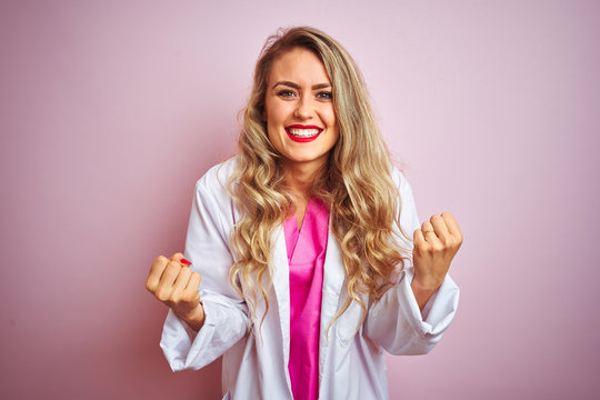 Young beautiful doctor woman standing over pink isolated background celebrating surprised and amazed for success with arms raised and open eyes. Winner concept.