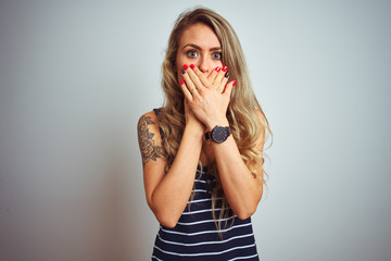 Young beautiful woman wearing stripes t-shirt standing over white isolated background shocked covering mouth with hands for mistake. Secret concept.