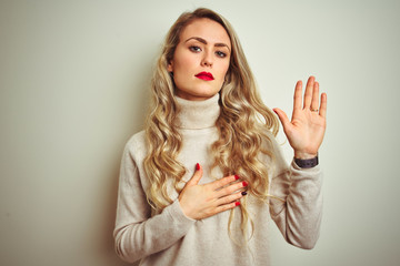 Beautiful woman wearing winter turtleneck sweater over isolated white background Swearing with hand...