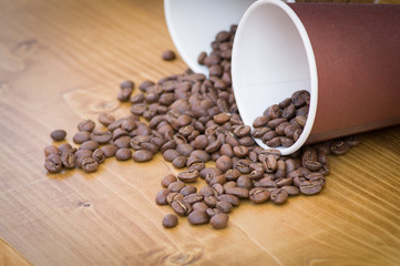Coffee beans spilling out of the cups on a wooden background on a street food festival