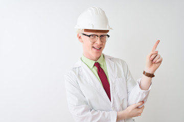 Albino scientist man wearing glasses and helmet standing over isolated white background with a big smile on face, pointing with hand and finger to the side looking at the camera.