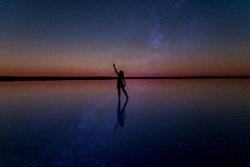 Silhoutte of girl dancing under milky way at Lake Tyrrell