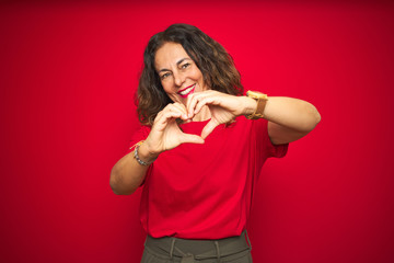 Middle age senior woman with curly hair over red isolated background smiling in love showing heart symbol and shape with hands. Romantic concept.