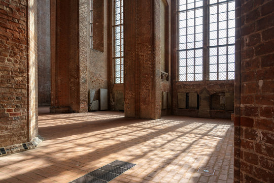 Sunlight shines through the high windows inside the St. Georgen Church, an historic brick building with arches and pillars in the old town of Wismar