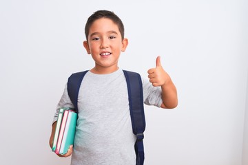 Beautiful student kid boy wearing backpack holding books over isolated white background happy with...